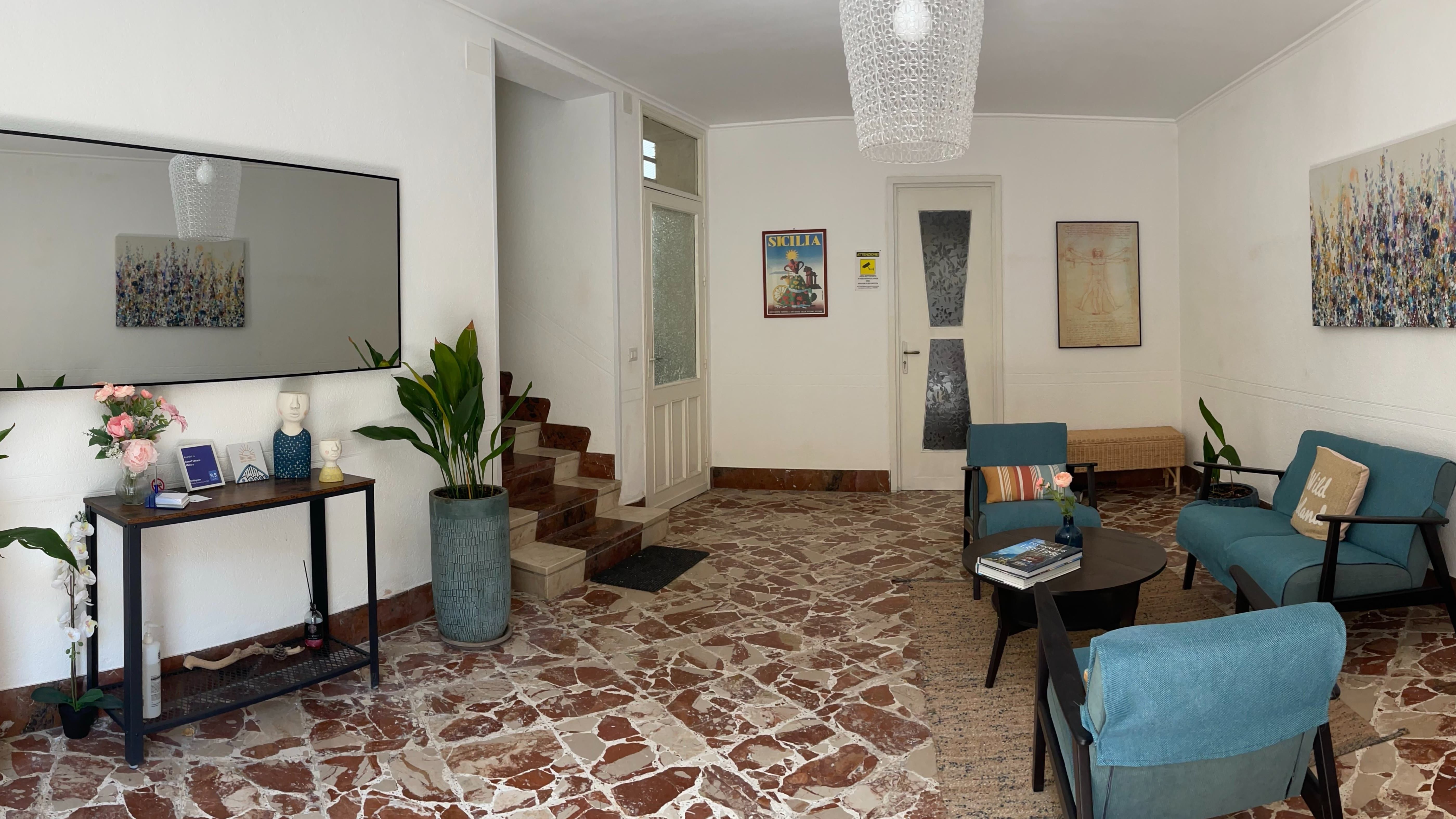 La hall di Sunset Terrace Mazara: poltrone, pavimento in marmo siciliano, e i tre gradini che portano alla porta a vetri