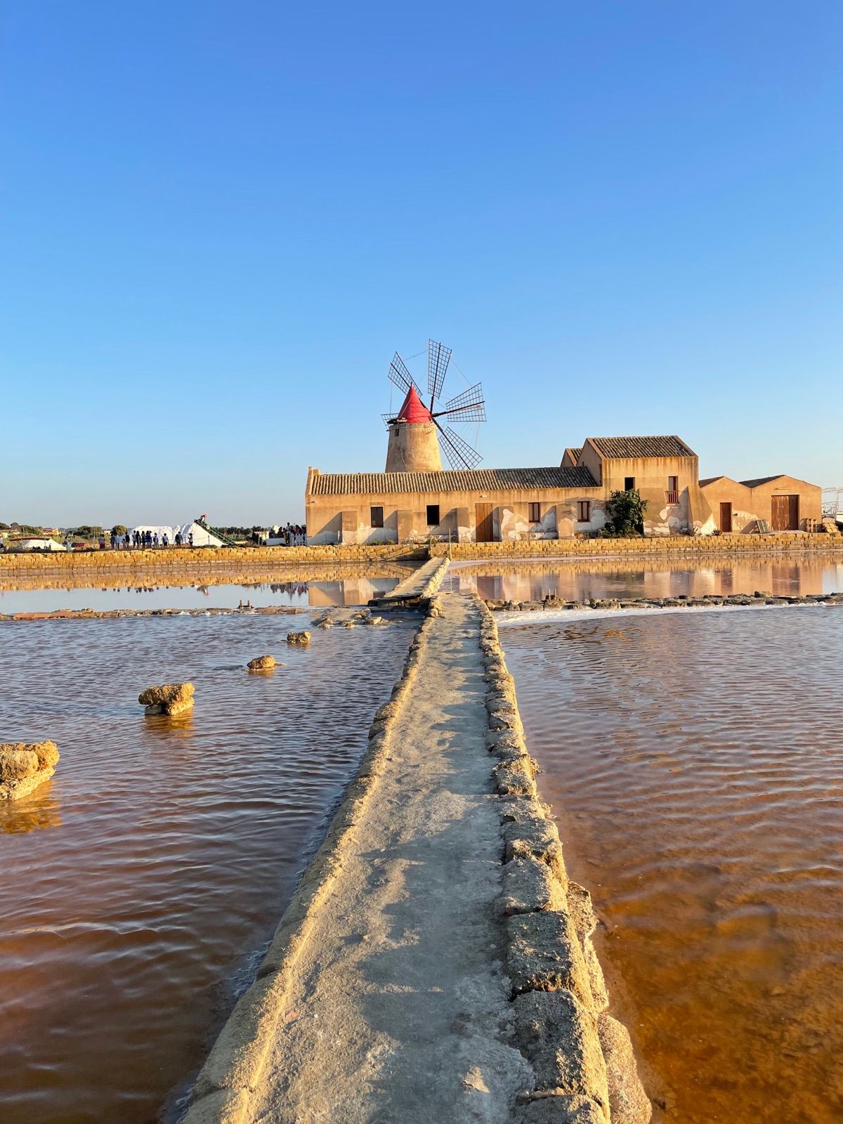 The windmill of the Marsala salt pans, its red cone reflected in the pink salt basins