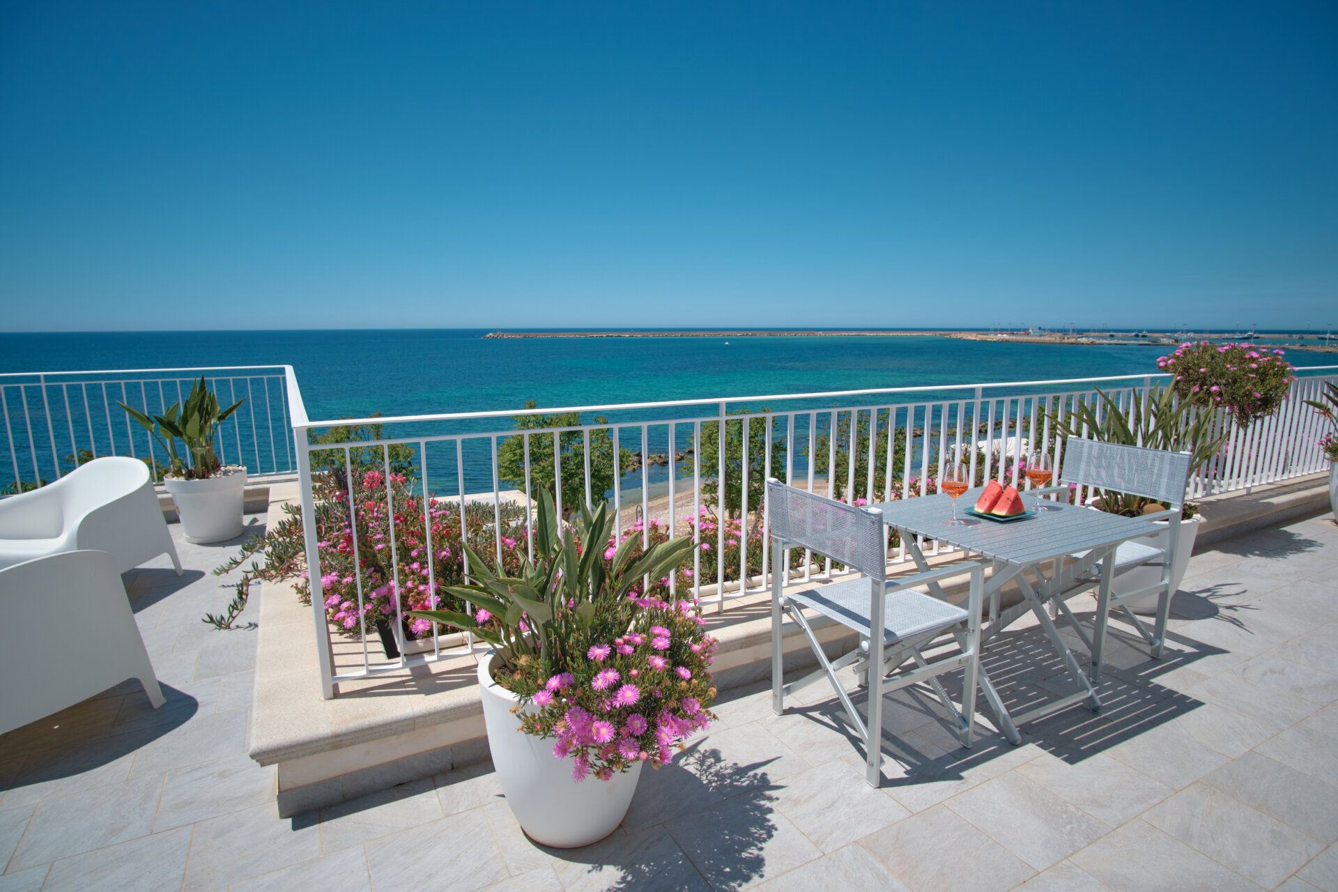 Un tavolo apparecchiato tra le bouganville, con il mare oltre — terrazza condivisa, Mazara del Vallo