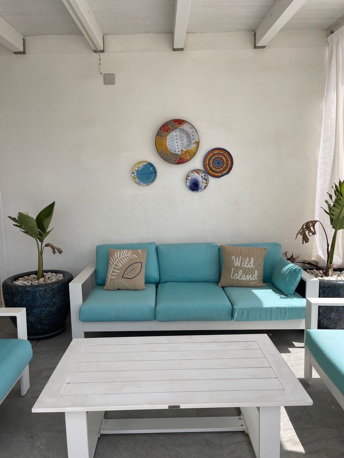 I divani all’ombra sulla terrazza condivisa, con i piatti di ceramica alla parete